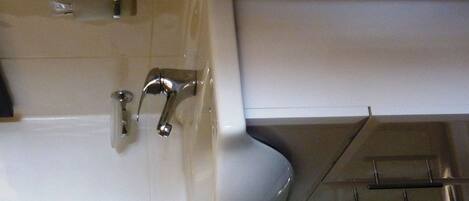 A bathroom with a white sink, a mirror, and a glass shower enclosure.