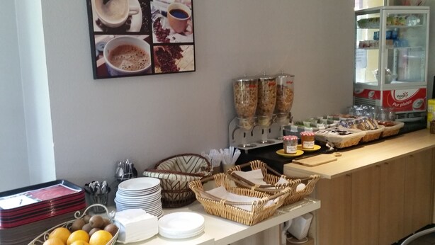 A breakfast buffet setup with coffee, cereal, and pastries.