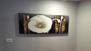 A room with a grey sofa, a red sofa, and a small table. There is a painting on the wall.