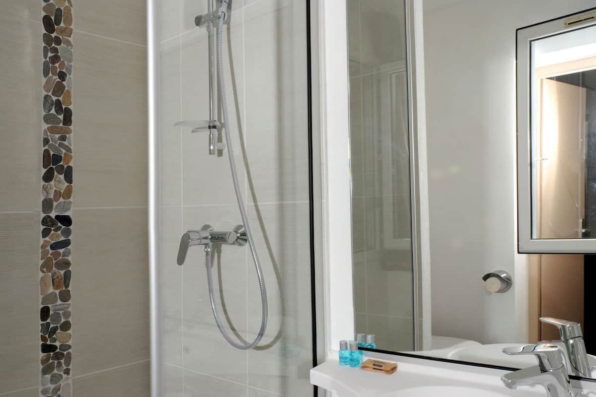 A modern bathroom with a glass shower enclosure, a white sink, and a mirror above it.
