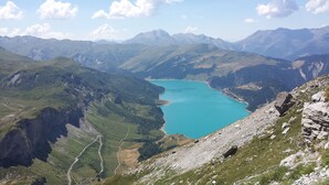 A mountainous landscape with a turquoise lake surrounded by rugged terrain and distant peaks.