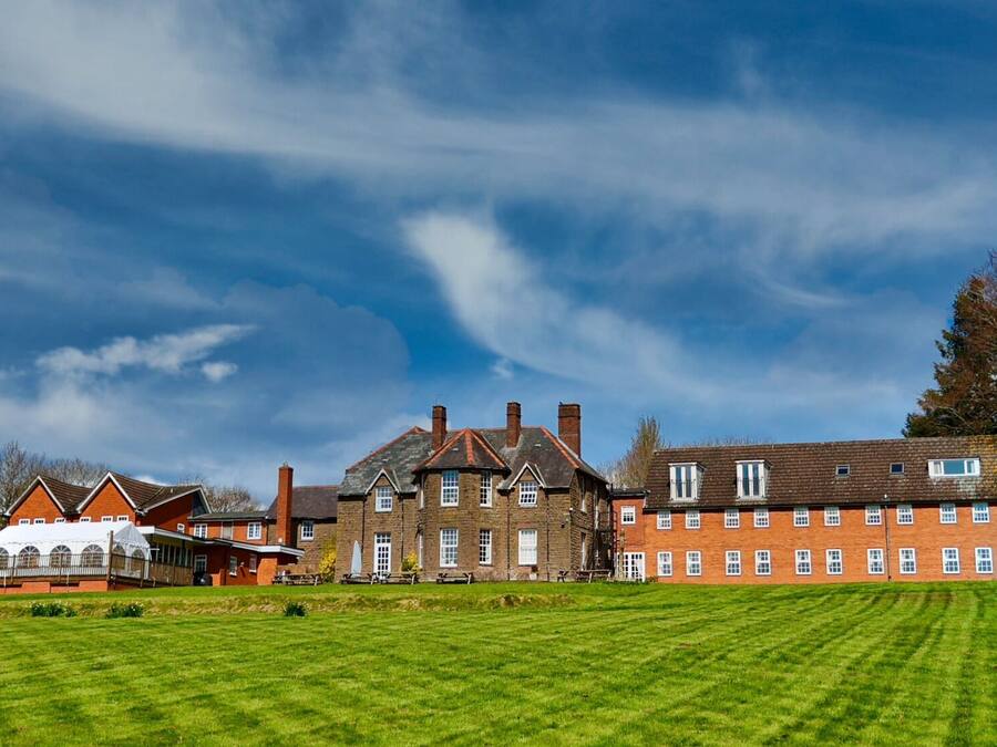 A large building with multiple windows and a lawn in front.