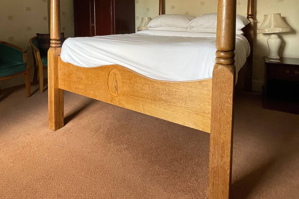 A four-poster bed with a wooden frame and a mattress.