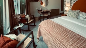 A hotel room with a large bed, a desk, a chair, a TV, and a window with curtains. - Pilgrim Hotel (Hereford)