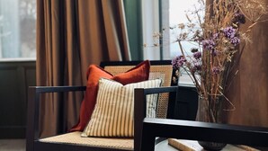A modern living room with a rocking chair, a small side table, and a vase with dried flowers. - Pilgrim Hotel (Hereford)