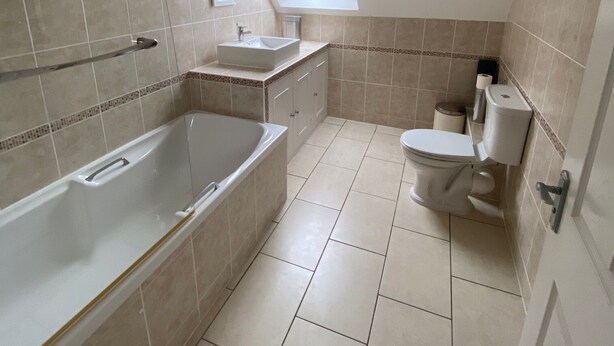 A modern bathroom with a skylight, a bathtub, a toilet, and a sink. - Pilgrim Hotel (Hereford)