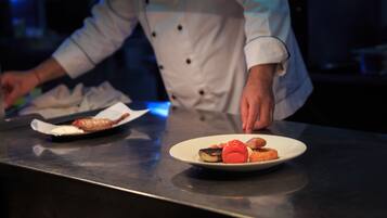 Un chef préparant des plats sur un plan de travail en acier inoxydable.