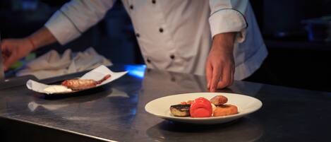 A chef preparing food on a stainless steel counter.