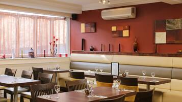 A restaurant with booths and tables, air conditioning, and artwork on the walls.