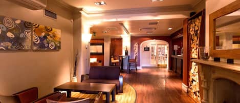 A hotel lobby with a wooden floor, seating area, and a fireplace.