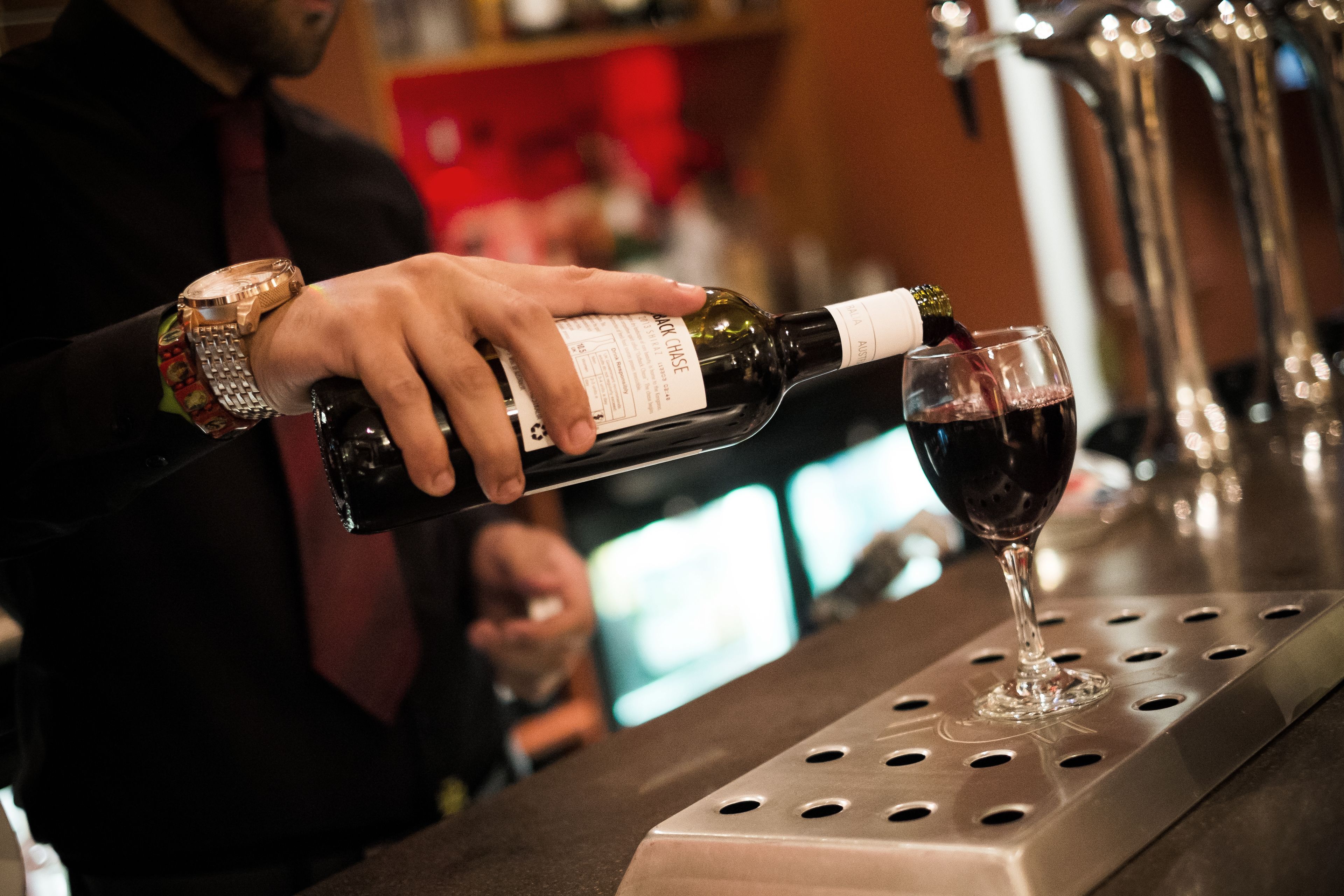 Una persona sirve vino en una copa en un bar.