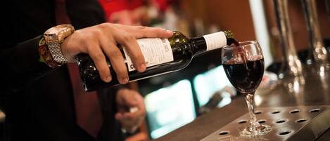 Una persona sirve vino en una copa en un bar.