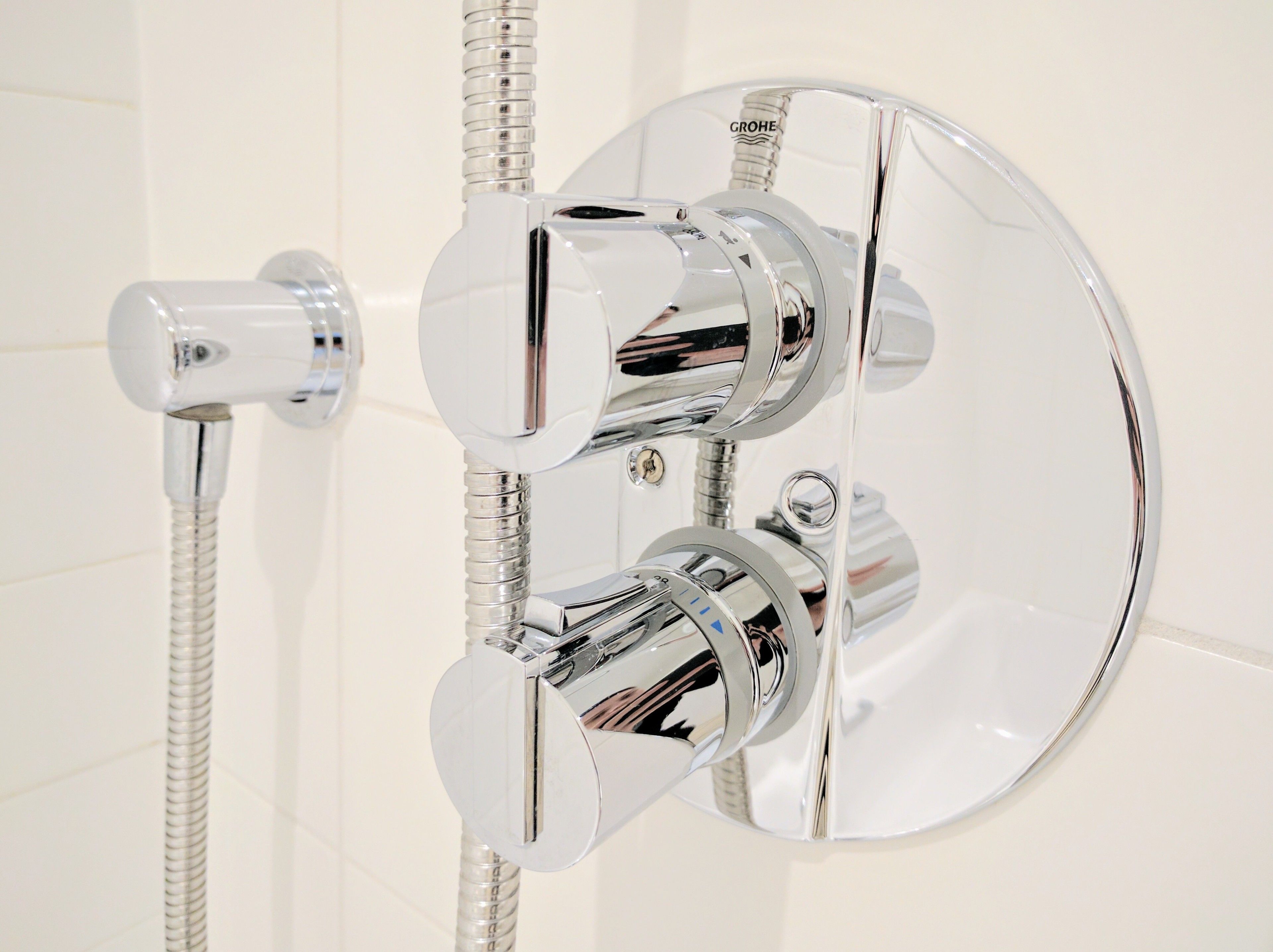 A chrome shower control with a flexible hose and a mirror.