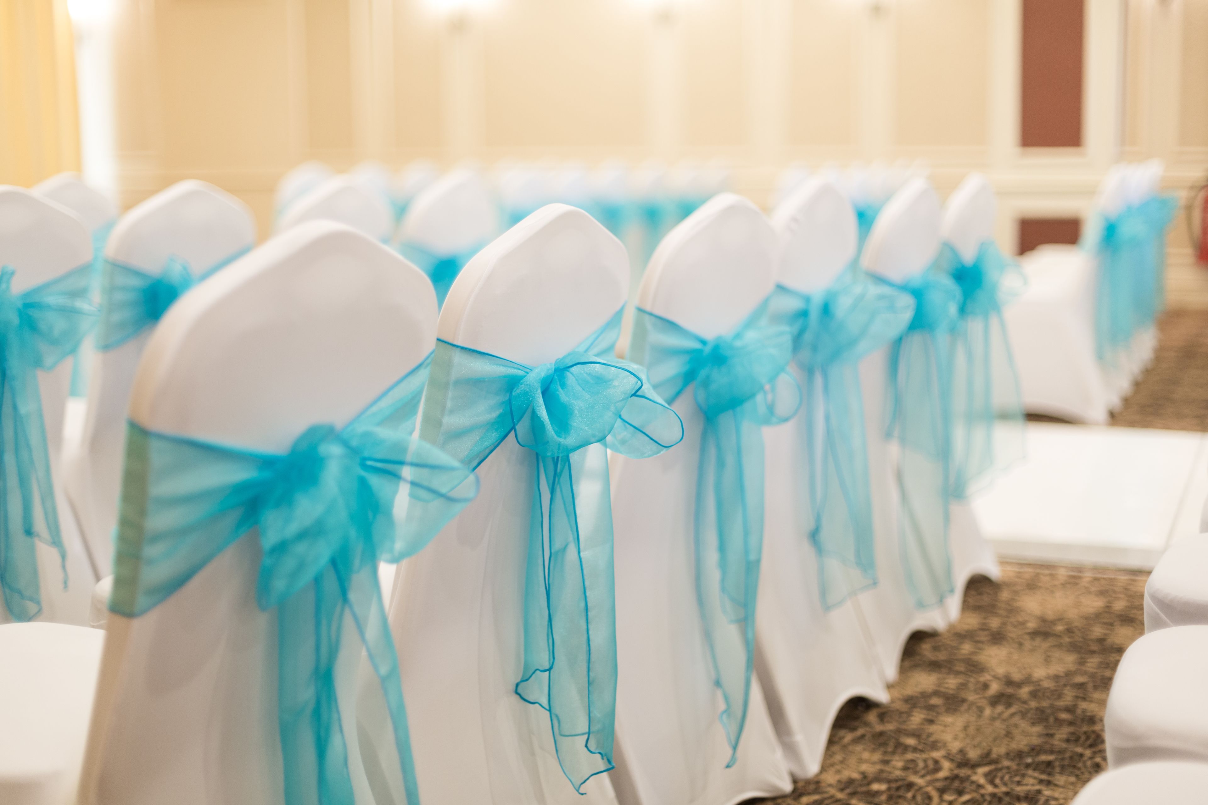 Rows of white chairs with blue sashes tied in bows.
