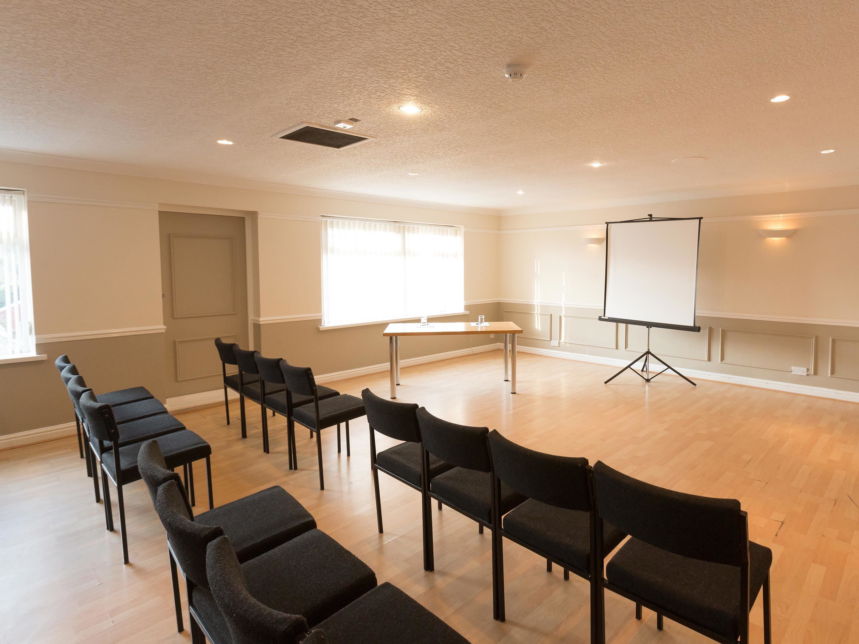 A conference room with a whiteboard, projector, and rows of chairs.