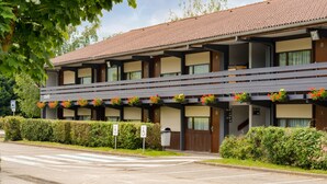 Un hotel con techo plano, varios balcones y jardineras.