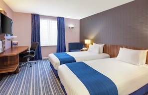 A hotel room with two beds, a desk, a chair, a TV, and a window with curtains. - Holiday Inn Express Poole by IHG (Poole)