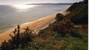A coastal beach with a clear sky, a sandy shore, and a grassy cliff. - Holiday Inn Express Poole by IHG (Poole)