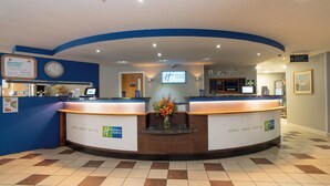 A hotel reception area with a clock, a reception desk, and a sign indicating breakfast is included. - Holiday Inn Express Poole by IHG (Poole)