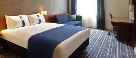 Una habitación de hotel con una cama grande, un escritorio y una silla.