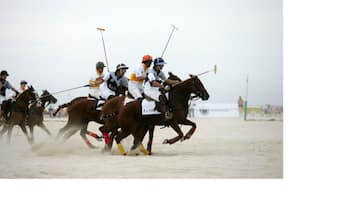 A polo match in progress with players on horseback, using mallets to hit a small ball.