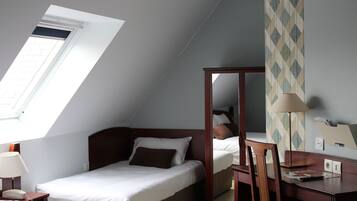 Una camera da letto con un soffitto spiovente, un letto, una scrivania e uno specchio.