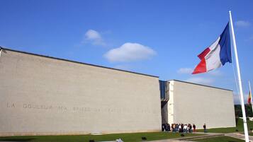 A building with a large inscription on its facade and a flagpole with a flag.