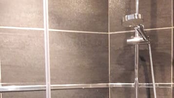 A shower with a handheld showerhead and a wall-mounted faucet.
