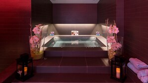A spa room with a large bathtub, two flower arrangements, and candles. - Royal Antibes (Antibes)