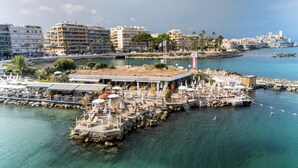 A waterfront hotel with outdoor seating, a flag, and a view of the cityscape. - Royal Antibes (Antibes)