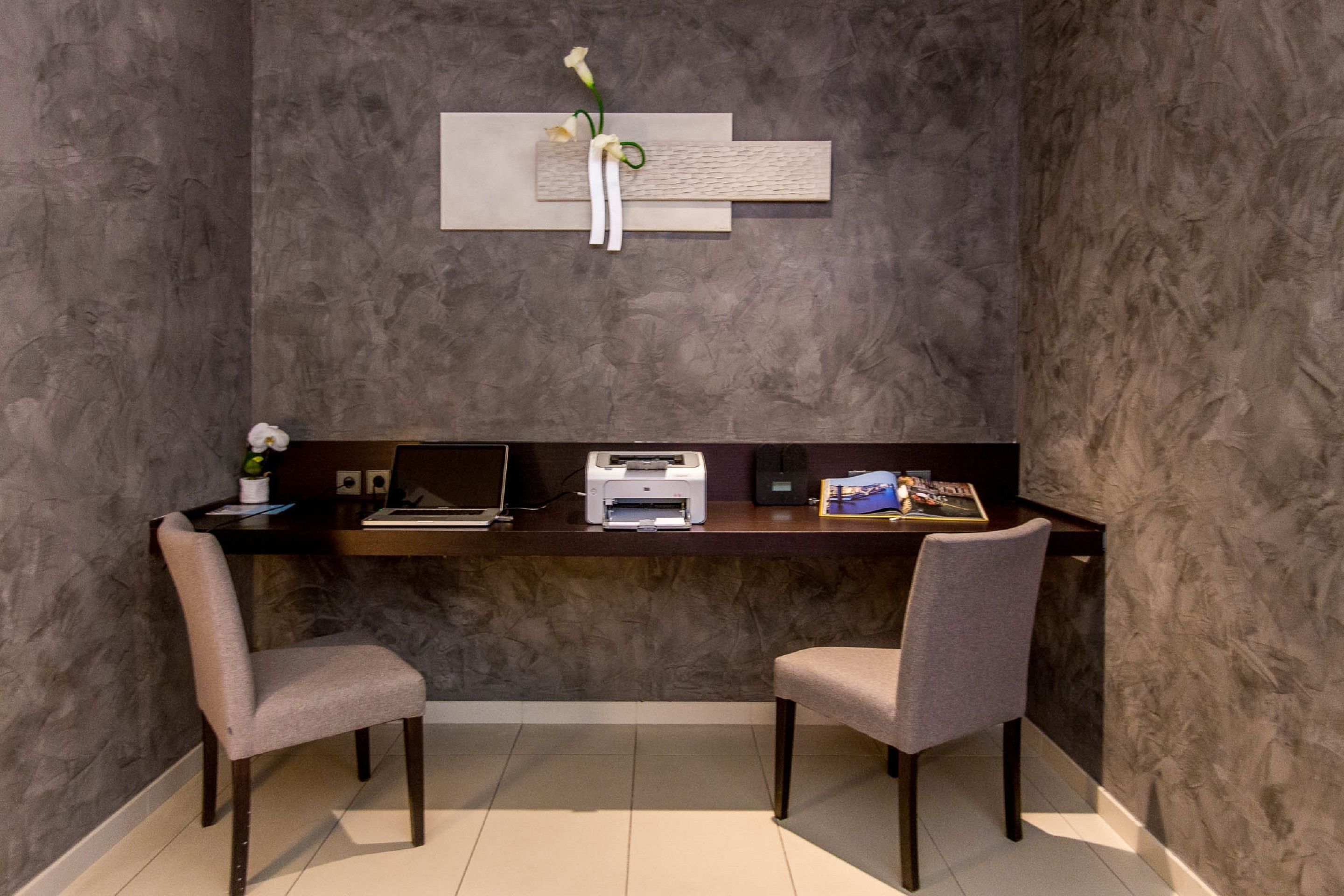 Un espace de bureau moderne comprenant un bureau, deux chaises, une imprimante et un élément décoratif mural.