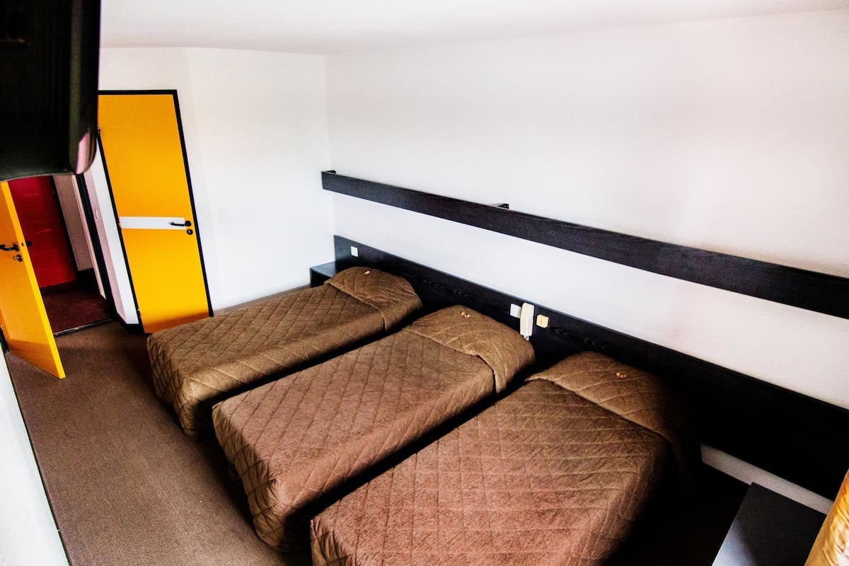 A small room with two single beds, a wardrobe, and a door.
