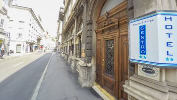 A hotel entrance with a sign reading "Nuovo Albergo Centro HOTEL" and a logo with a car and stars.