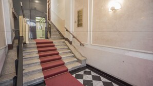 A staircase with red carpeted steps and a checkered floor pattern. - Nuovo Albergo Centro (Trieste)
