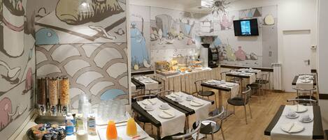 Un restaurante con varias mesas dispuestas para comer, una zona de buffet y un televisor montado en la pared.