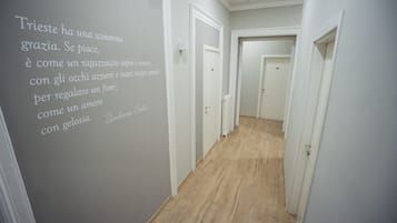 Un pasillo con paredes blancas y suelo de madera que conduce a varias puertas.