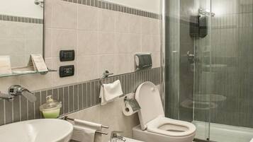 A modern bathroom with two sinks, a toilet, and a glass-enclosed shower.