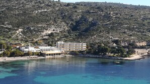 A coastal building with multiple floors, situated near a clear blue sea.