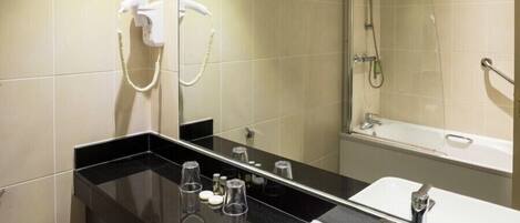 A modern bathroom with a black countertop, a white sink, a mirror, a handheld showerhead, and a toilet paper holder.