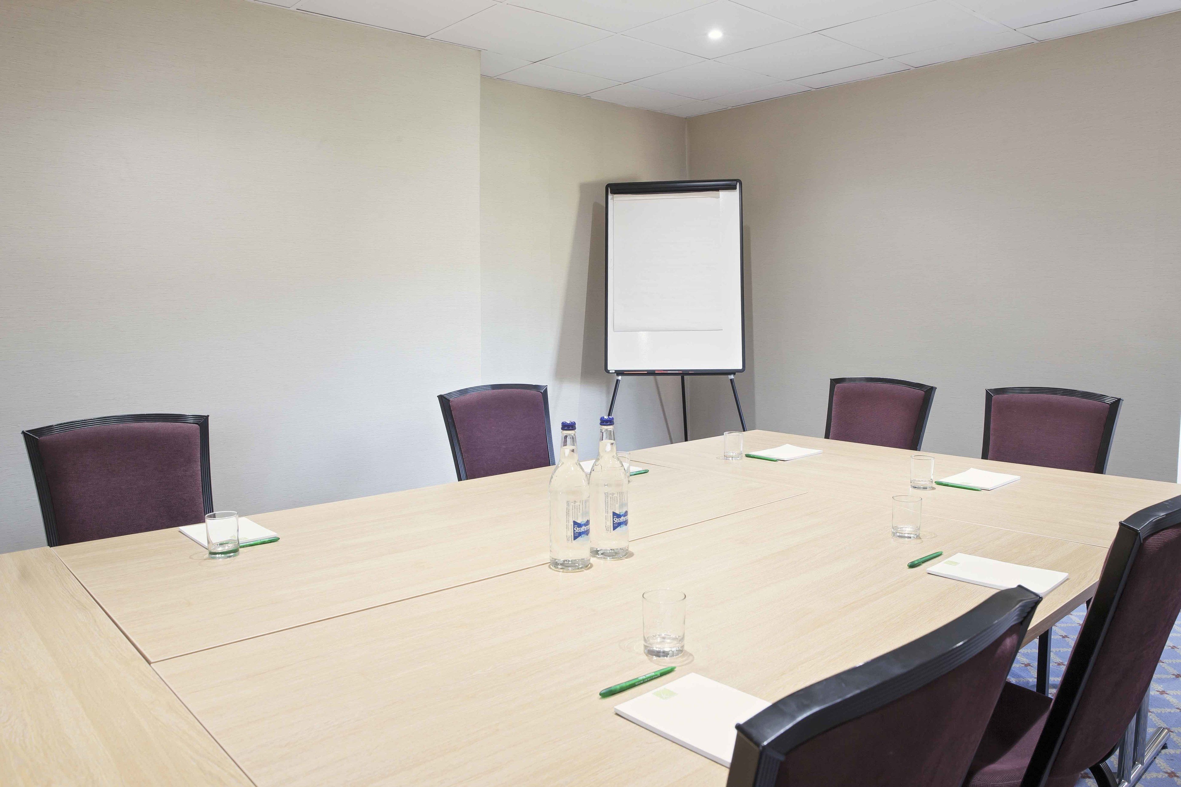 A conference room with a large table, chairs, a whiteboard, and water bottles.