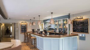 A bar area with a wooden counter, hanging copper pendant lights, and a menu board displaying food and drink prices. - Kings Court Hotel, BW Signature Collection (Alcester)