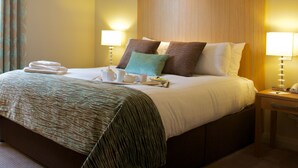 A hotel room with a large bed, two bedside lamps, a wooden headboard, and a window with curtains. - Kings Court Hotel, BW Signature Collection (Alcester)