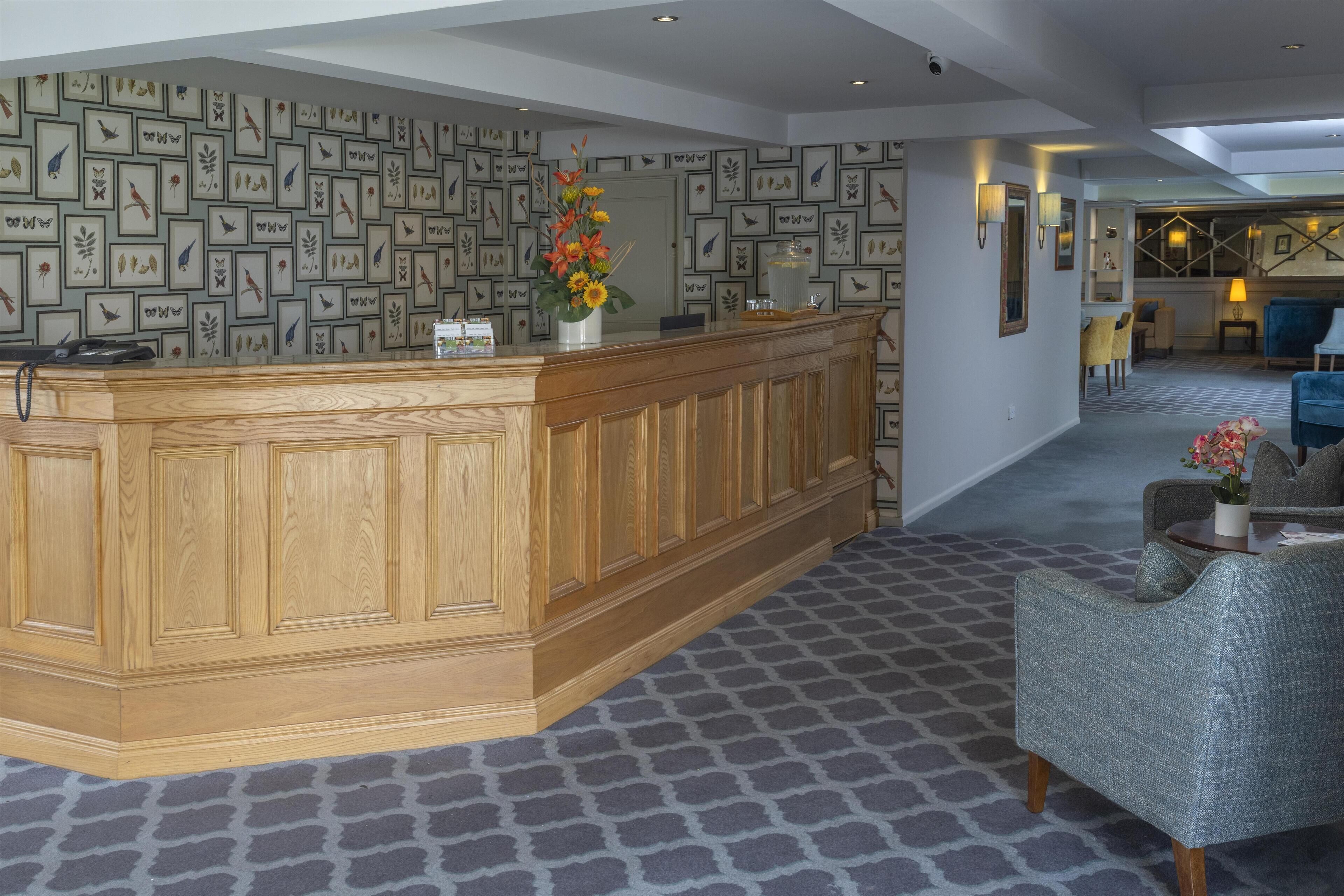 A reception area with a wooden counter, framed wall art, and a patterned carpet.