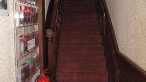 Un escalier recouvert de moquette, avec un extincteur et des magazines accrochés au mur.