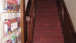 Un escalier recouvert d’un tapis rouge et doté de rampes en bois, menant à l’étage supérieur.