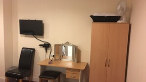 Une pièce comprenant un bureau, une chaise, une armoire, un téléviseur fixé au mur et un miroir.
