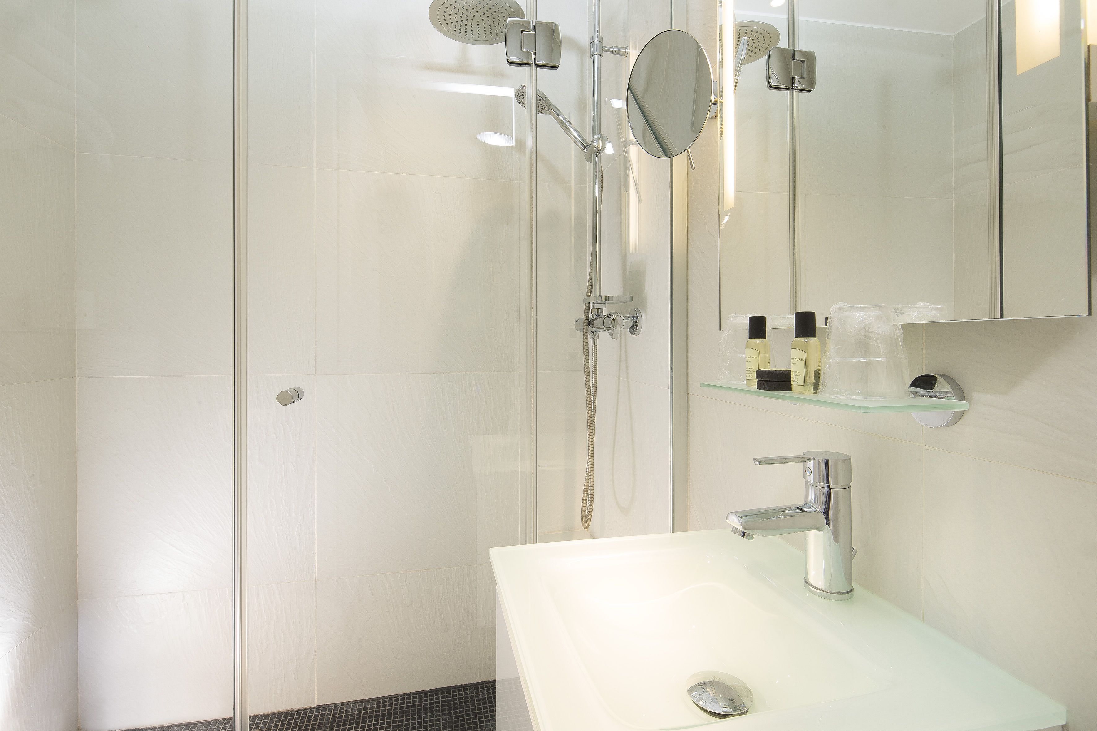 A modern bathroom with a glass shower enclosure, a white sink, and a mirror above the sink.