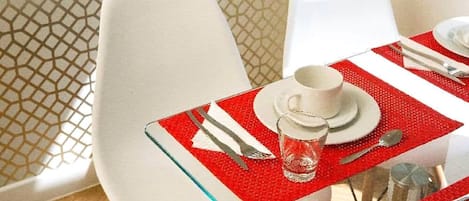Un tavolo da pranzo apparecchiato con piatti bianchi, posate e un bicchiere.