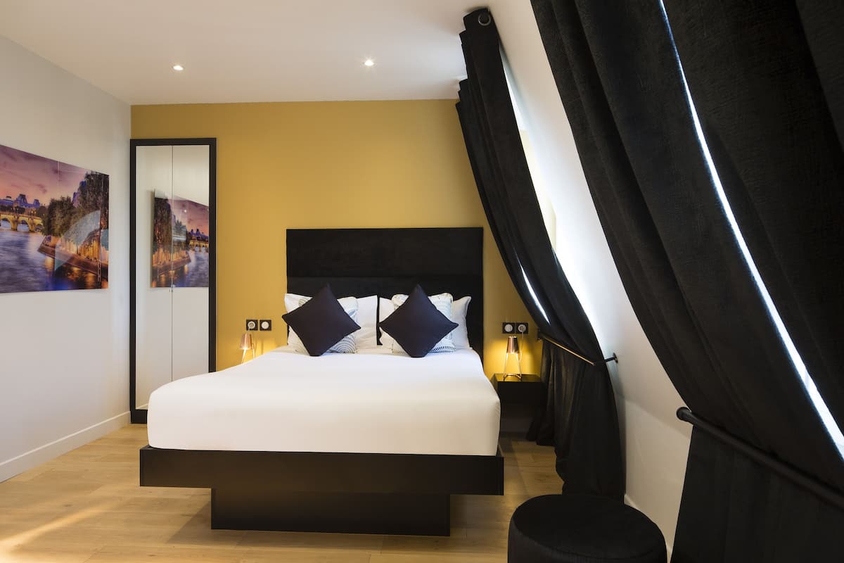A modern bedroom with a large bed, a headboard, bedside lamps, and a painting on the wall.