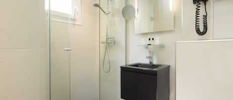 A modern bathroom with a glass-enclosed shower, a black sink, and a mounted telephone.